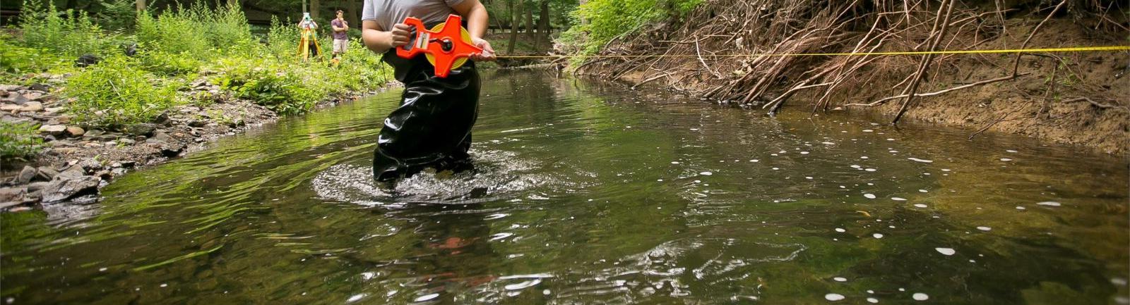 坦普尔环境研究专业的学生站在树林里的小溪里做实验.