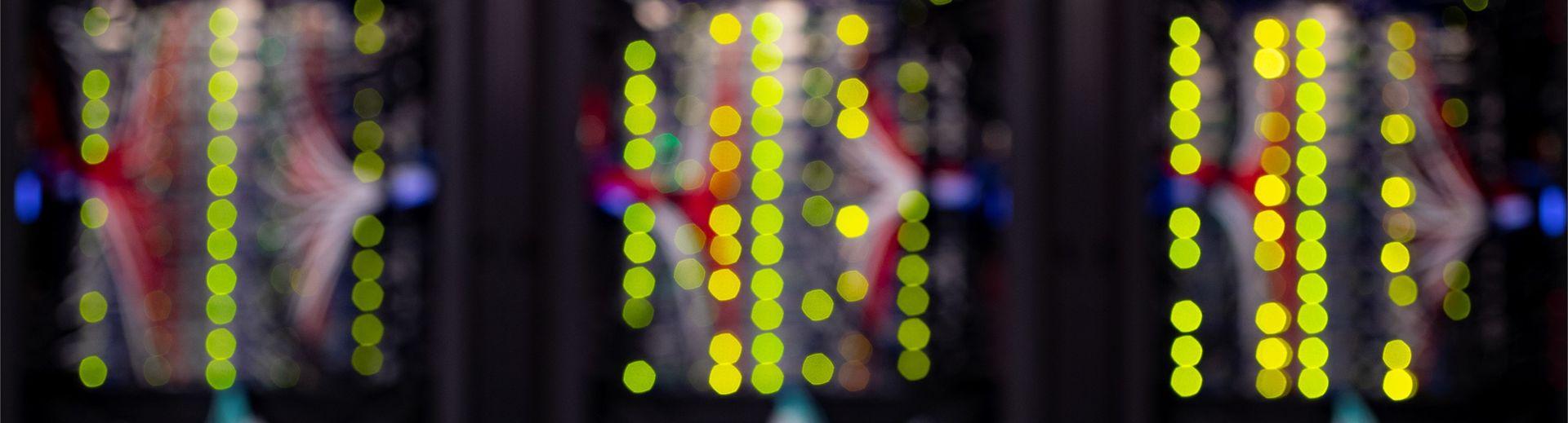 Blurred image of 的 back of computer servers resulting in a very primary colorscape with columns of bright yellow circles.