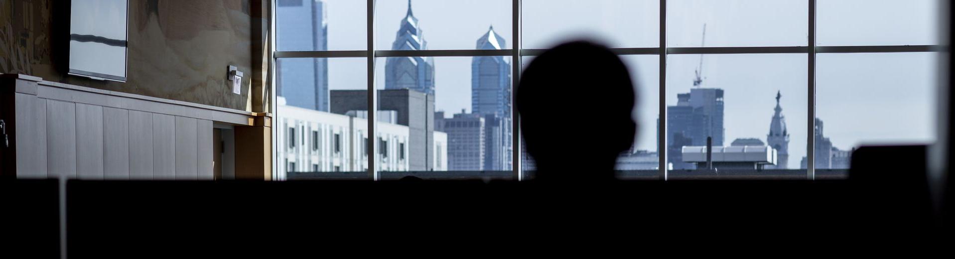 A student looks at the Philadelphia skyline through the windows of a building at 亿德体育.
