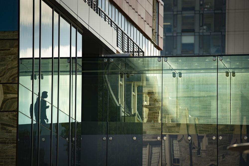 一名学生走过天普主校区建筑物之间的玻璃桥.